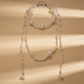 Barokke meerlaagse parelketting met zilveren accenten op een minimalistische achtergrond - Ketting-Wit