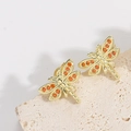 Golden dragonfly stud earrings with red crystal wings on a textured stone display - Dragonfly Style (ES2655-4)