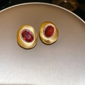 Detailed close-up of 18k gold plated stud earrings with ruby and diamond halo on gold tray - Ruby Halo / Pink
