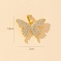 Detailed close-up of a 2cm gold butterfly pendant with sparkling cubic zirconia on beige paper - S-Micro Inlaid Butterfly (1.8x2cm)