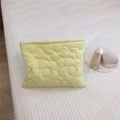 Detailed macro view of yellow quilted makeup bag with embossed floral texture and zipper - Light Yellow