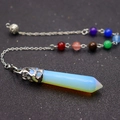 Macro shot of opal hexagonal crystal pendant with chakra beads and intricate metal casing - Opal
