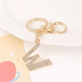 Macro shot of gold letter W keychain with rhinestones on a white ceramic tray - Letter W