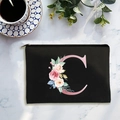 Neceser minimalista de lona negra con letra C floral sobre superficie de mármol - Letra C
