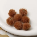 Close-up of brown plush ball charms with gold metal rings for DIY jewelry making - Brown