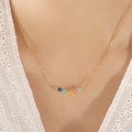 Gouden titanium ketting met vijf kleurrijke emaille smileys gedragen door een model - Goud
