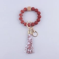 Dettaglio portachiavi con perle in silicone rosso e marrone e nappa in pelle PU decorativa - Palla da rugby