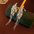 Detail of silver leaf tassel earrings displayed on a dark green jewelry stand - Wheat Tassel Style / Silver