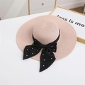 Detail of pink straw sun hat with a black ribbon bow and elegant pearl embellishments - M / Pink