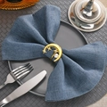 Detailed view of a gold moon and star napkin ring with pearl on a blue linen cloth - Pearl Moon 18K Gold