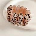 Close-up of leopard print resin beads on an elastic bracelet against a white dish - Pink