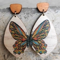 Orecchini bohémien in legno con farfalle colorate presentati su una base di pietra naturale - Ali di farfalla colorate