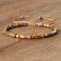Adjustable woven bracelet with natural earth-tone stones and gold spacers on wood - No.29 Crazy Lace Agate