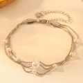 Detalle de una pulsera de tres capas de acero inoxidable con diversas perlas blancas - Color Acero