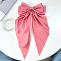 Pink satin bow hair clip with long streamers on a stylish desktop background - Watermelon red