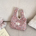 Detail der floralen Lunchtasche mit weichem Sherpa-Futter und Cord-Textur auf Sofa - Beige