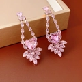 Close-up of pink heart-shaped zircon earrings with leaf accents on a leather surface - Silver Needle Studs / Pink