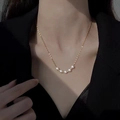 Minimalist gold titanium necklace with five white pearls worn on a female neck - Gold