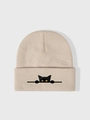 Close-up of a beige knitted beanie featuring a black cartoon cat embroidery detail - One Size / Beige