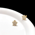 Detail of elegant gold flower stud earrings with white enamel petals on a ceramic dish - White Gold Flower Ear Bone Stud (Single)