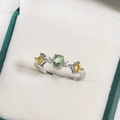 Silver flower ring with green oval gemstone and yellow side stones in a jewelry box - Green Oval with Yellow Square and White Round Stones Style (白金色25)