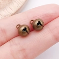 Pair of vintage bronze alloy bells for DIY jewelry making shown on fingertips - 8mm / Bronze
