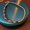 Collier de perles œil de tigre avec détails dorés et fermoir mousqueton sur socle - Collier de Perles Dorées Et Œil de Tigre
