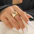 Dettaglio di un ampio anello placcato oro con design geometrico a piramide indossato da una modella - Cono piramidale geometrico dorato