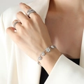 Bracciale a margherita in argento lucido con anelli minimalisti sulla mano di una modella - Color Acciaio