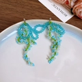 Detail of handcrafted blue and green seed bead floral earrings on a white ceramic plate - 16# Silver Needle-Blue-Bow