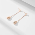 Boucles d'oreilles pendantes goutte or rose avec zircon sur fond géométrique blanc - Or rose