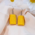 Vista macro di orecchini di mais realistici in resina su un fondo in seta beige - Mais / Giallo / Gancio d'Argento