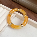 Chunky acrylic amber tube bracelet with golden spacer beads on a cream jewelry tray - Yellow