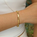 Brazalete minimalista de acero inoxidable dorado pulido para mujer puesto en la muñeca - Dorado