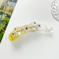 Macro detail of three-petal floral banana clip with crystal rhinestones on yellow acrylic - Yellow