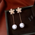 Dettaglio macro di orecchini a fiore placcati oro 18k con perle bianche in scatola portagioie - Oro