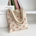 Dettaglio ravvicinato di una borsa in maglia beige con motivi floreali rossi vivaci - Fiore a Cinque Petali / Beige