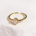 Detailed macro of gold adjustable ring featuring an oval zircon on a stone surface - White Gemstone Gold Base