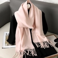 Soft pink cashmere-style scarf with tassel trim displayed on a black top - Flesh Pink