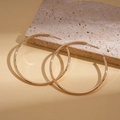 Macro shot of large polished golden geometric hoop earrings leaning against a textured stone - Silver Pin - Gold 5cm
