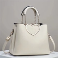 Close-up of a white tote bag featuring a gold heart-shaped buckle and lychee texture - White