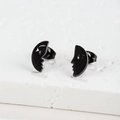 Macro view of matte black asymmetrical face silhouette stud earrings on white stone - Abstract Face / Black
