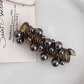 Detail of a spiral brown hair tie with metallic grey beads on a white ceramic plate - Black/Dark Grey Beads
