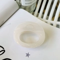 Detailed view of a creamy oval resin hair claw clip placed on a magazine for styling - Approx 7cm / Jelly White