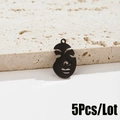 Vista de detalle de 5 colgantes de cara abstracta de metal negro sobre piedra beige - Negro