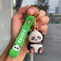 Close-up of a cute 3D panda keychain with a green silicone wrist strap and golden clasp - Bamboo Strap - Waving Panda