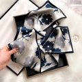Blue and grey silk scarf with floral print and dark blue border, held in hand - Bluebell Flower