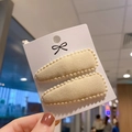 Detail view of beige faux cashmere teardrop BB clips with small bead trim on card - Beige