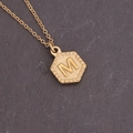 Macro shot of gold-plated hexagon pendant featuring the letter M with radiant texture - Letter M (13#M)