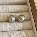 Close-up of minimalist dark silver pearl stud earrings on linen jewelry tray - 12mm / Gray